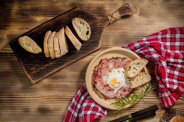 Plate of breakfast with fried eggs, bacon and bread.