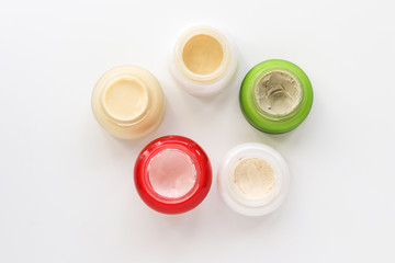 Top view of assortment of open various cosmetic creams on white background. Natural handmade skincare cosmetics. Choice of treatment. Beauty concept
