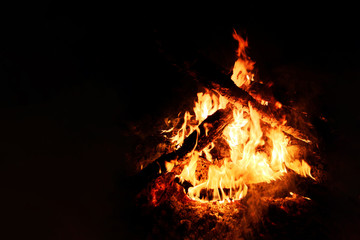 Close-up of a burning beautiful bonfire on a black night background, burning hot glowing logs, high resolution