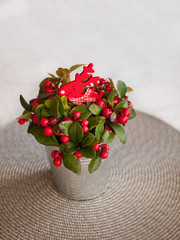 Eastern teaberry (Gaultheria procumbens) on table with red wooden reindeer. Christmas decoration.
