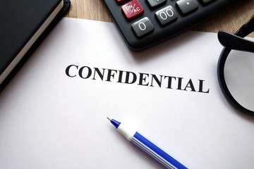 Confidential document, calculator, pen and glasses on   desk