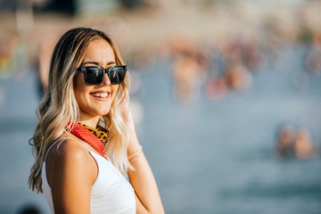 Smiling woman with sunglasses standing at the Beach