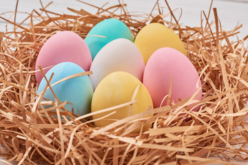 Obraz na płótnie Canvas Easter background. Colorful easter eggs in paper nest on a white background, close up