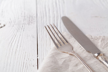 Knife, fork with linen serviette on the white background