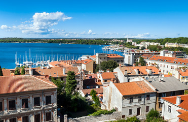 Obraz premium Panoramic view of Pula with orange tile buildings roofs and blue harbor, Istria region, Croatia