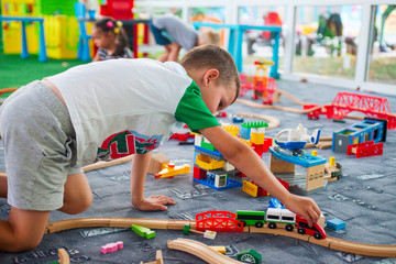 Little child playing with wooden railway on the floor. Little boy playing with wooden train set
