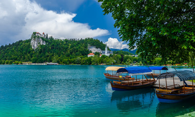 Fototapeta premium Boats at the pier that help one to trip to the island in the middle of the Bled lake and ringing the bell of the 17th century church. Slovenia.