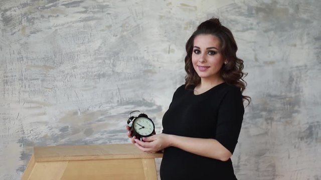 Beautilul future mother look at the clock. Pregnant woman in black body suit. Happy future mother. belly