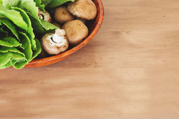 Bowl of mushrooms and lettuce on wooden cutting board