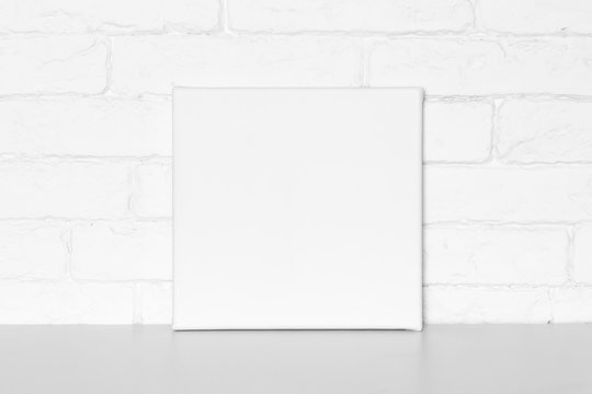Blank square canvas in interior. Brick wall on background.
