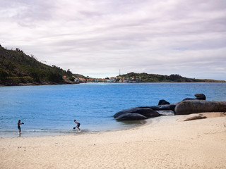 Dos niños jugando en la preciosa playa de arena blanca y mar azul intenso en Ézaro, Galicia.