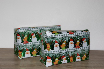 zwei hintereinander stehende geschenke in buntem papier fografiert in farbe zu hause in...