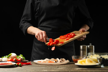 Chef pours cherry tomatoes in a plate. Frost in motion. For preparing pizza, tomato sauce, salad....
