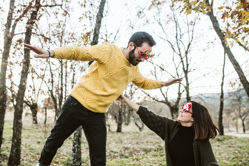 .Two friends enjoying their free time on the outdoor field. Both wear Christmas glasses, funny props, leisure time. Lifestyle.