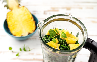 Top view of blender with pineapple and spinach peaces