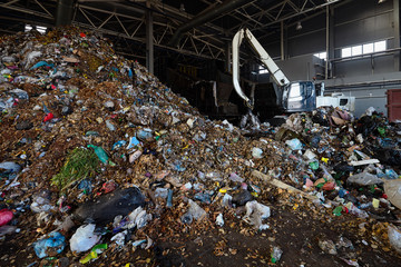 Modern recycling plant process of unloading garbage, manipulator loads garbage on conveyor for...