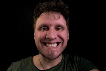 Fototapeta premium Joyfully laughing young man. Scoffs his teeth. Mad look into the camera.