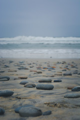 Fototapeta na wymiar Soft Tumbled Rocks in Front of a Hazy Ocean Shore