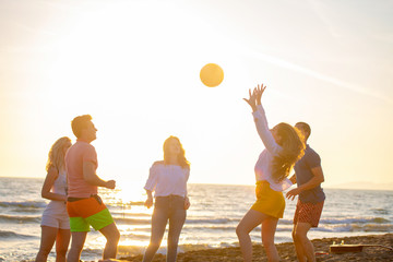 Group of young people playing volleyball on the beach