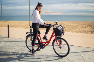 Woman riding bicycle along beach sand at summer time. Healthy and sport concept