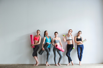 Fototapeta na wymiar Group of female friends in sportswear together standing in a gym after yoga.