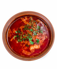 Borsch in brown plate isolated on white. Red traditional beetroot soup closeup.