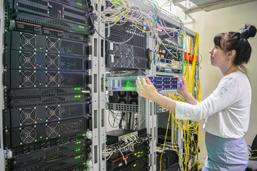A woman installs a new server in a modern data center.Girl system administrator works with powerful...