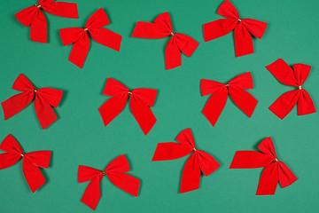 Twelve red bows on green background.