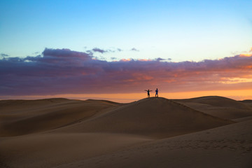 Fototapeta na wymiar Silhouette of two men taking picture of dusk scenery at famous dunes in Maspalomas, Gran Canaria, Spain