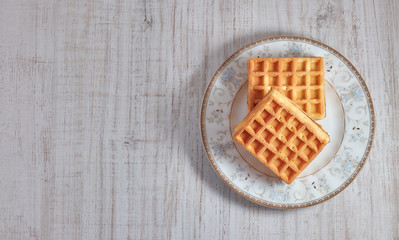 Top view sweet fresh Viennese waffles on plate isolated on wooden table. copy space. European for breakfast.