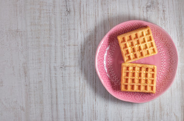 Fototapeta na wymiar Top view sweet fresh Viennese waffles on plate isolated on wooden table. copy space. European for breakfast.
