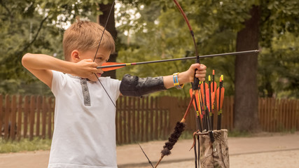 Boy directed arrow at a target. Child with bow and arrow concentrated on target. Kid stared at...