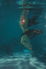 Fototapeta na wymiar beautiful girl in a transparent jumpsuit with rhinestones on the whole body swims underwater as a free diver