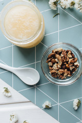 Walnuts, honey and white flowers on table