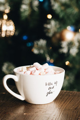 Female hand holding delicious sweet marshmallows in white cup
