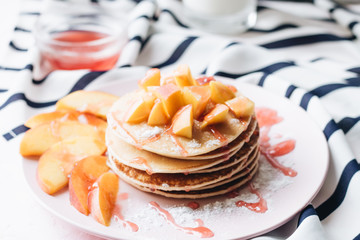 Stack of delicious homemade pancakes with sauce and sliced apple