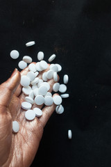 Female hand and pile of scattered white pills