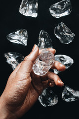 Female hand and ice cubes on black background