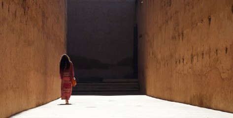 Lady walks away down a high-walled alley
