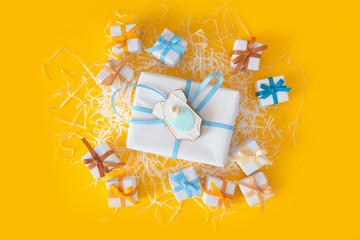 Baby shower cookies. White big and small gifts with blue ribbons. Yellow background