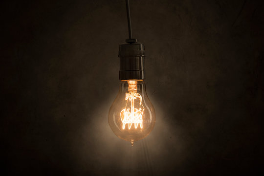 Incandescent Light Bulb Hangs In The Dark Room