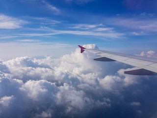 Fototapeta premium Airplane wing above the clouds and a blue sky