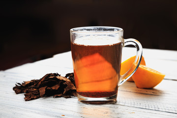 Cup of hot tea, dried tea leaves and lemon wedges
