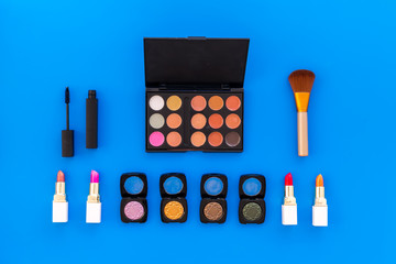 Professional cosmetics set with palette of eyeshadows on blue background top view