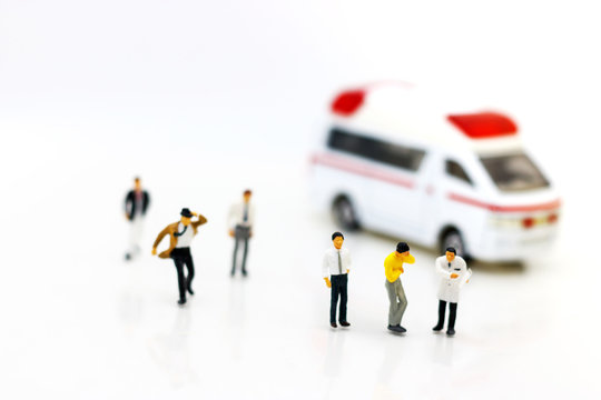 Miniature people: Doctor and patient standing with ambulance. Health care and emergency concept.