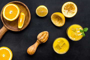 Squeeze fresh oranges with juicer. Orange juice in glass near half cut oranges on black background...