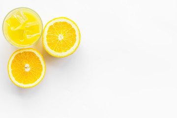 Fototapeta na wymiar Glass of cold orange juice near halfs of fresh oranges on white background top view space for text