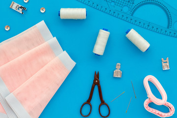 Tailor shop with thread, scissors, fabric. Sewing as hobby. Blue background top view