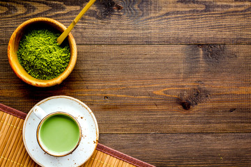 Coffee and cocktails with matcha concept. Matcha latte near bowl with matcha powder and accessories on dark wooden background top view space for text