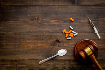 Drugs addiction, arrest for drugs. Pills, spoon with powder, syringe on dark wooden background top...